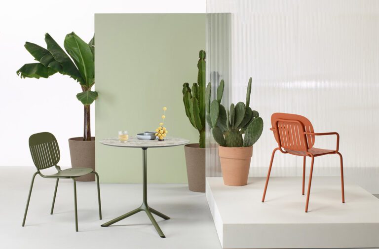 Modern patio furniture with plants and table.