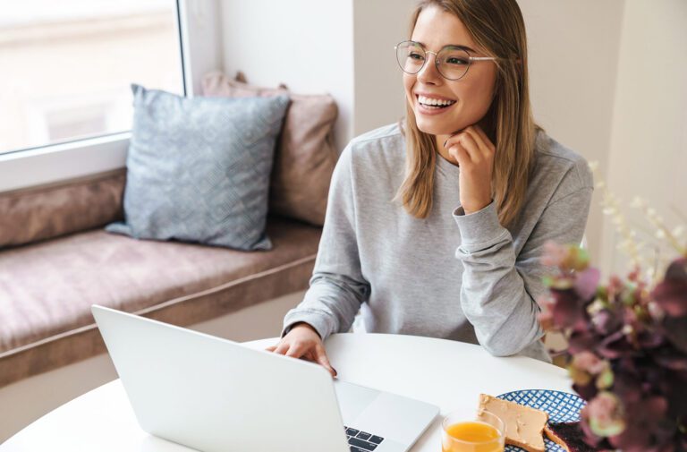 Smiling woman using laptop at home.
