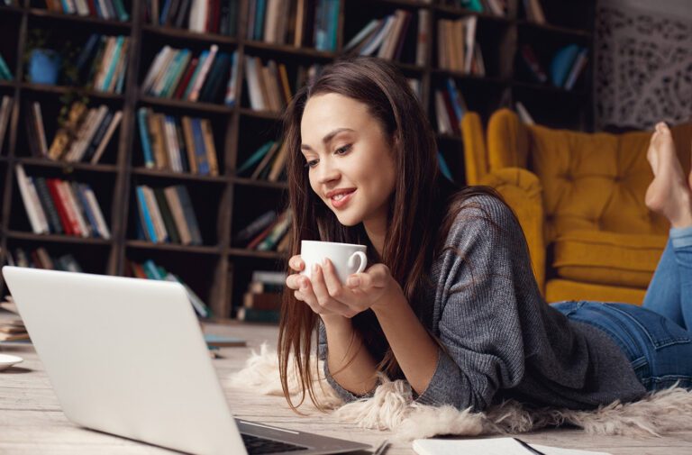 Woman enjoying coffee while using laptop.