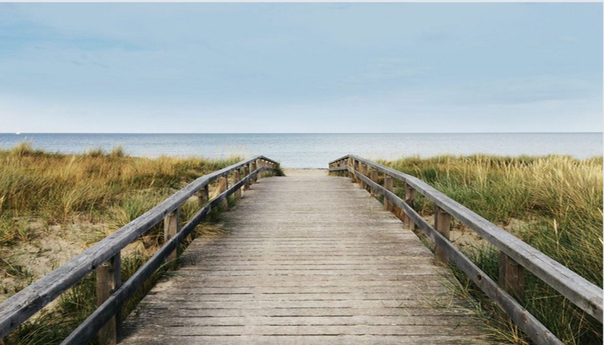 Wooden boardwalk leading to sandy beach.